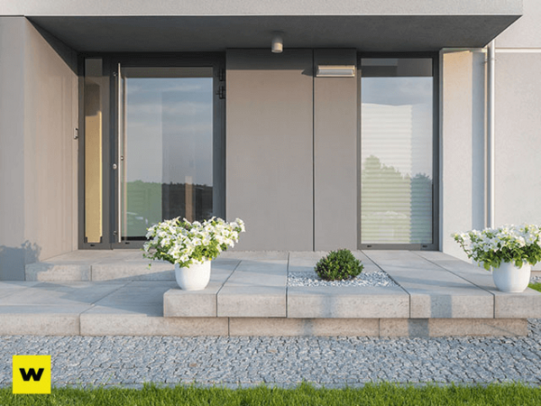 Moderner Hauseingang mit großen Glasflächen, Pflanzkübeln und stilvoller Steinplatte.